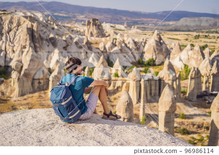 Young man exploring valley with rock formations and fairy caves near Goreme in Cappadocia Turkey Young man exploring valley with rock formations and fairy caves near Goreme in Cappadocia Turkey 96986114