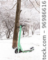 Green rental scooter standing near beautiful tree covered with snow 96986616