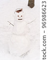 Cute white snowman standing at the snowy trees background 96986623
