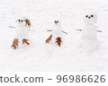 Cute three white snowmen standing at the snowy ground background 96986626