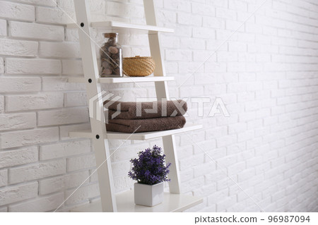 Clean soft towels and plant on shelves near white brick wall. Space for text 96987094