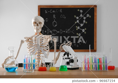 Skeleton and different chemistry glassware in classroom 96987154