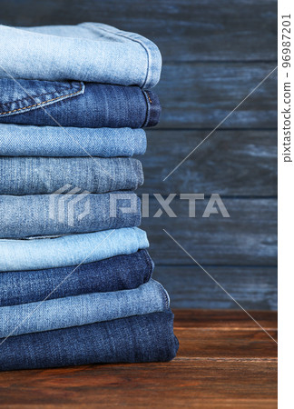 Stack of different jeans on wooden table. Space for text Stack of different jeans on wooden table. Space for text 96987201