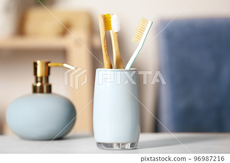 Bamboo toothbrushes in holder on light table indoors, closeup 96987216