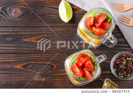Healthy salad in glass jars on wooden table, flat lay. Space for text 96987455