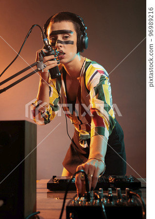 Musician girl using mixer turntables for musical performance, mixing techno music as dj performer. Cool artist adjusting volume and bass key on electronics stereo equipment, audio insturment. 96989216