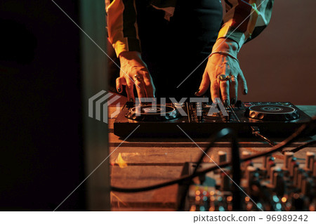 Female musician using mixing turntables to play music at party, having fun with audio dj equipment for techno performance. Playing stereo sounds with electronics, microphone and headphones. 96989242