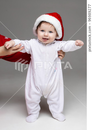 Adorable baby in Santa hat and white footie. Adorable baby in Santa hat and white footie. 96989277