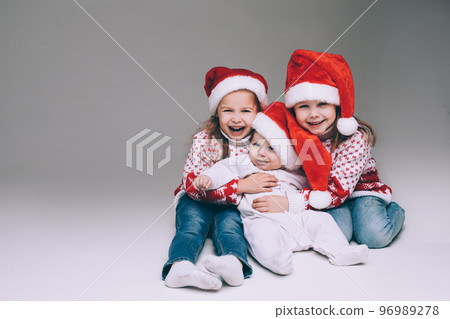 Laughing sisters with baby brother at xmas. Laughing sisters with baby brother at xmas. 96989278