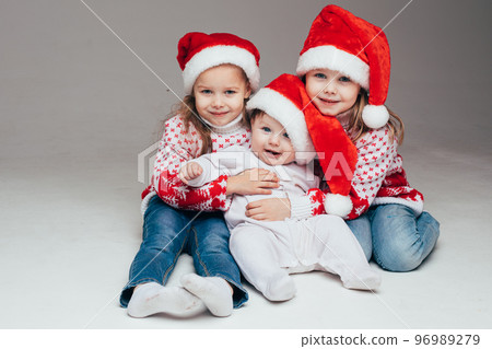 Laughing sisters with baby brother at xmas. Laughing sisters with baby brother at xmas. 96989279