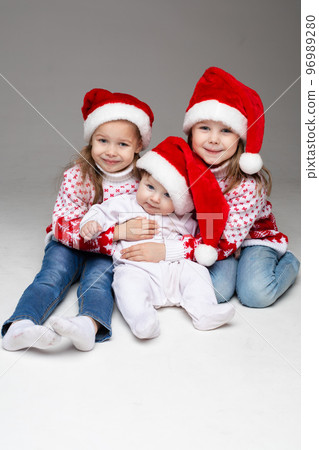 Laughing sisters with baby brother at xmas. Laughing sisters with baby brother at xmas. 96989280