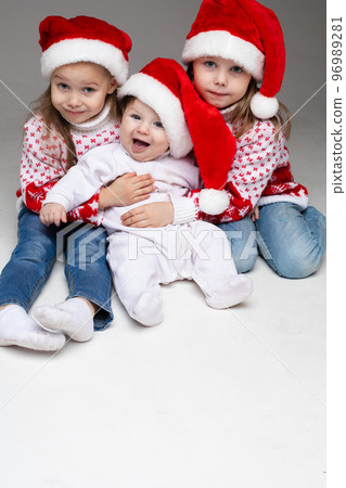 Laughing sisters with baby brother at xmas. Laughing sisters with baby brother at xmas. 96989281