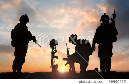military man kneeling in front of Fallen Soldier grave during sunset military man kneeling in front of Fallen Soldier grave during sunset 96990915