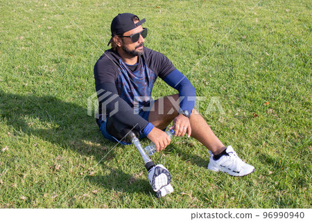 Tired man with prosthetic leg relaxing after training 96990940