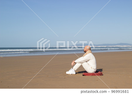 Lonely middle aged man in scarf sitting on beach 96991681