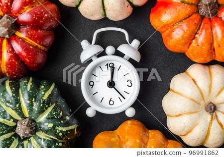 An alarm clock and pumpkins on the black table. An alarm clock and pumpkins on the black table. 96991862