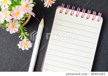 The Spiral notebook and wooden pencil with flower on black cardboard. The Spiral notebook and wooden pencil with flower on black cardboard. 96991863