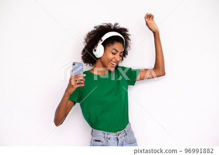 Portrait of excited young woman dancing in headphones 96991882
