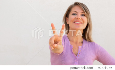 Cheerful Caucasian woman showing victory sign 96991976