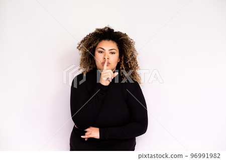 Confident young woman making hush gesture Confident young woman making hush gesture 96991982