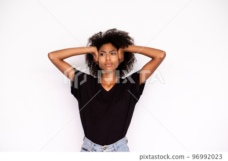 Portrait of frowning young woman covering ears with hands 96992023