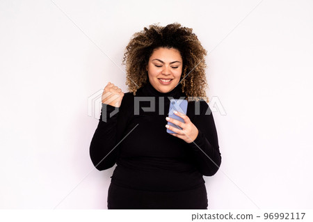 Satisfied young woman looking at smartphone screen 96992117