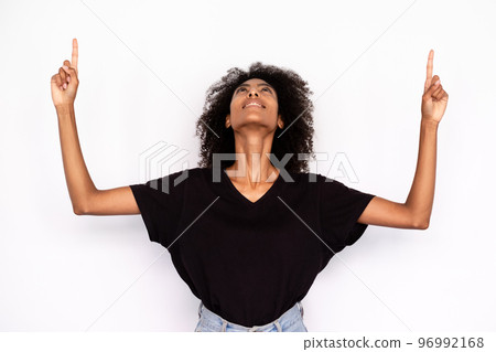 Portrait of happy young woman pointing upwards Portrait of happy young woman pointing upwards 96992168