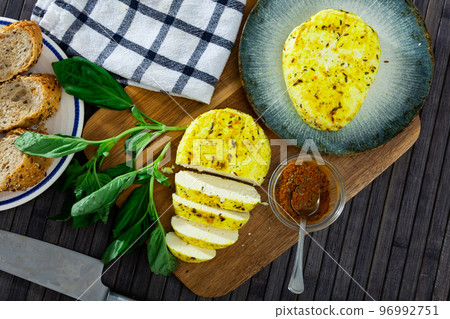 Slices of spicy roasted cottage cheese with turmeric and cumin on wooden board Slices of spicy roasted cottage cheese with turmeric and cumin on wooden board 96992751