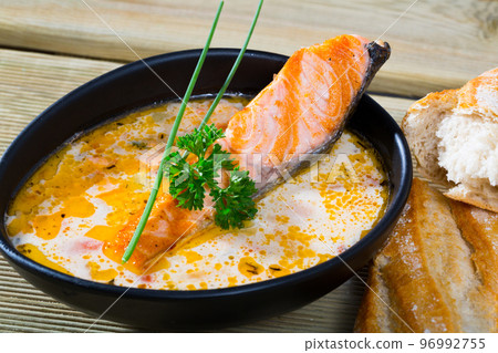 Delicious cream soup with salmon, served in bowl with bread at table Delicious cream soup with salmon, served in bowl with bread at table 96992755