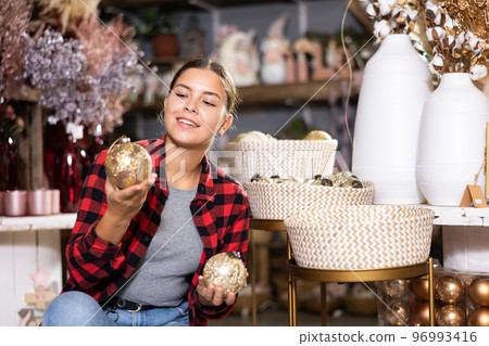 Woman is choosing decorations for Christmas tree in market indoor Woman is choosing decorations for Christmas tree in market indoor 96993416