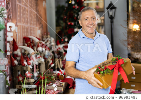 Portrait of an elderly man with box of gifts in Christmas present shop Portrait of an elderly man with box of gifts in Christmas present shop 96993485
