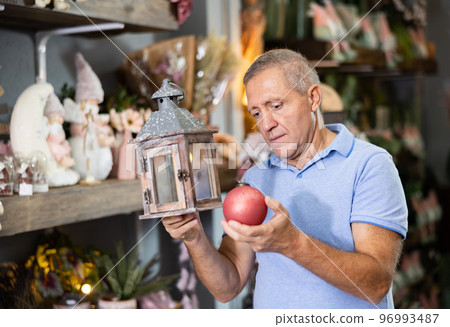 Middle-aged male consumer choosing Christmas decorations in a shopping mall at the December Middle-aged male consumer choosing Christmas decorations in a shopping mall at the December 96993487