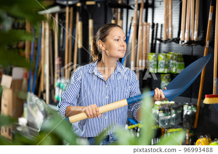 Positive woman purchasing new spade in shop Positive woman purchasing new spade in shop 96993488