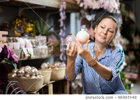 Cheerful woman selecting baubles in store 96993548
