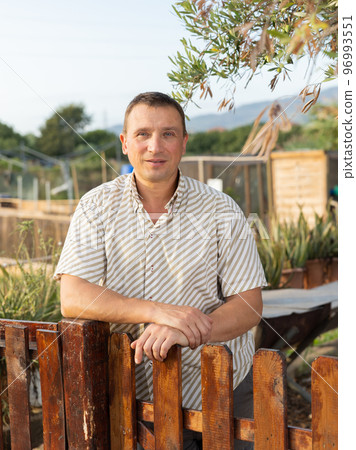 Male farmer posing at fence of his farm on summer day 96993551
