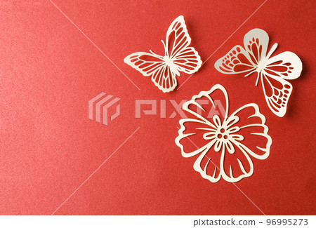 A carve of white paper butterfly and flower on a red cardboard background. A carve of white paper butterfly and flower on a red cardboard background. 96995273