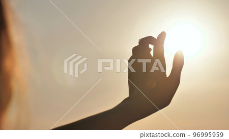 The girl touches the sunset sun the fingers. Romantic concept. 96995959