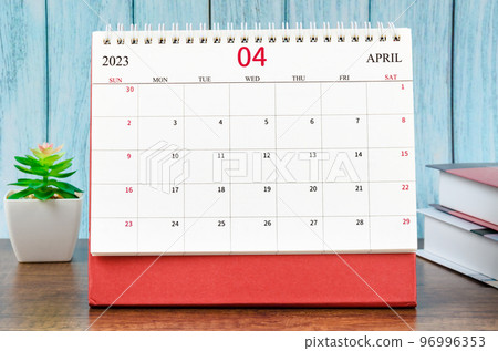 The April 2023 Monthly desk calendar for 2023 year with the books on blue wooden background. 96996353