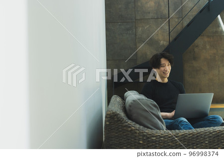 A man looking at a computer in the living room A man looking at a computer in the living room 96998374