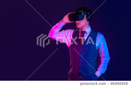 Metaverse concept. Asian businessman wearing vr goggles virtual reality headset posing on dark color background. 96998408