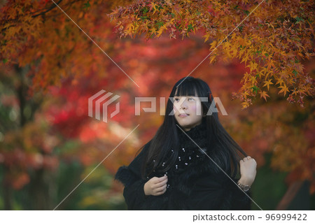 A young woman in the background of autumn leaves in Hattori Ryokuchi, Toyonaka, Osaka Prefecture 96999422