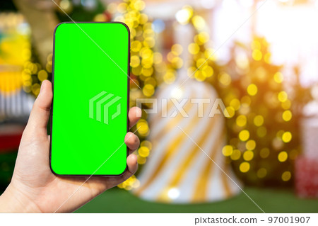 Close-up of female use smartphone blurred images with Colorful balls on Green Christmas tree background Decoration During Christmas and New Year,Green screen 97001907