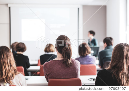 Female speaker giving presentation in lecture hall at university workshop . Participants listening to lecture and making notes. Scientific conference event. Female speaker giving presentation in lecture hall at university workshop . Participants listening to lecture and making notes. Scientific conference event. 97002407