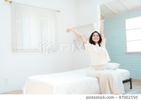 Young woman stretching in bedroom 97002550