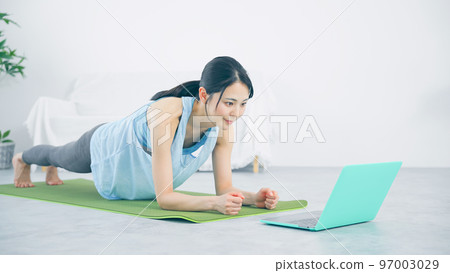 A woman training while looking at a computer Plank trunk training 97003029