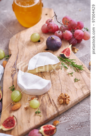 Sliced Camembert or brie cheese on wooden cutting board at domestic kitchen Sliced Camembert or brie cheese on wooden cutting board at domestic kitchen 97004429