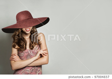 Glamorous Woman in Summer Dress and wide pink broad brim hat against White Wall Background, Fashion 97004837