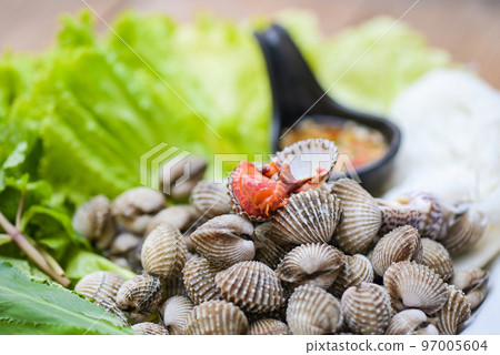 Cockle shellfish seafood plate with fresh vegetable herbs and spices on plate food Cockles background - blood cockle peeled on table with seafood sauce 97005604