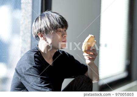 A young man eating bread 97005803