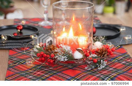 Festive table set in the living room for Christmas and New year in loft style. Christmas tree, black plates and forks, woven napkins, trendy tableware, cozy interior of the house 97006994